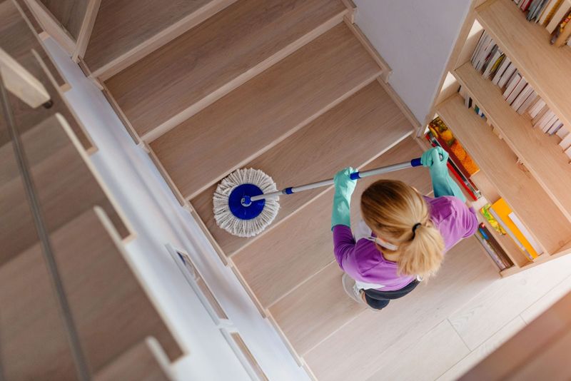 Cleaner mopping wooden stairs in a home